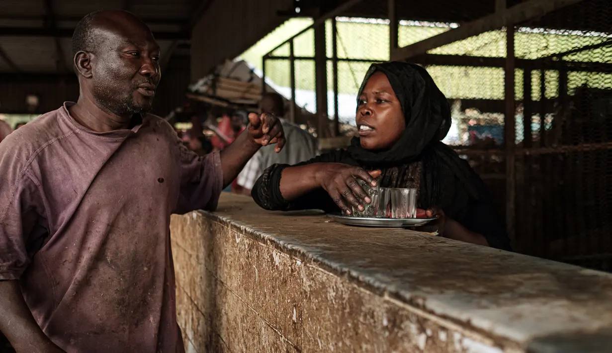 Seorang wanita berbicang dengan pegadang ikan setelah menjual teh di sebuah pasar ikan di dekat Sungai Nil, di kota kembar Khartoum, Omdurman (24/6/2019). Kota Omdurman didirikan pada tahun 1884. (AFP Photo/Yasuyoshi Chiba)