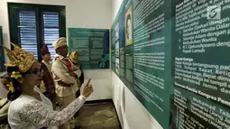 Pengunjung mengenakan kostum adat dan pejuang memerhatikan kutipan pesan kebangsaan di Museum Sumpah Pemuda, Jakarta, Jumat (27/10). Jelang peringatan 89 tahun Sumpah Pemuda, museum ini ramai dikunjungi masyarakat. (Liputan6.com/Faizal Fanani)