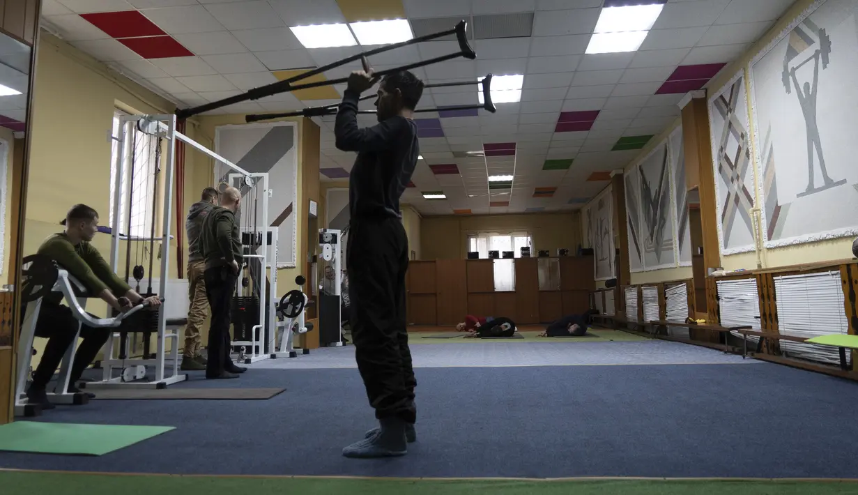 Ivan Moroz, yang terluka saat bekerja di fasilitas produksi gas, berolahraga bersama tentara Ukraina di ruang terapi fisik di pusat rehabilitasi di wilayah Kharkiv, Ukraina, pada 30 Desember 2022. (AP Photo/Vasilisa Stepanenko)