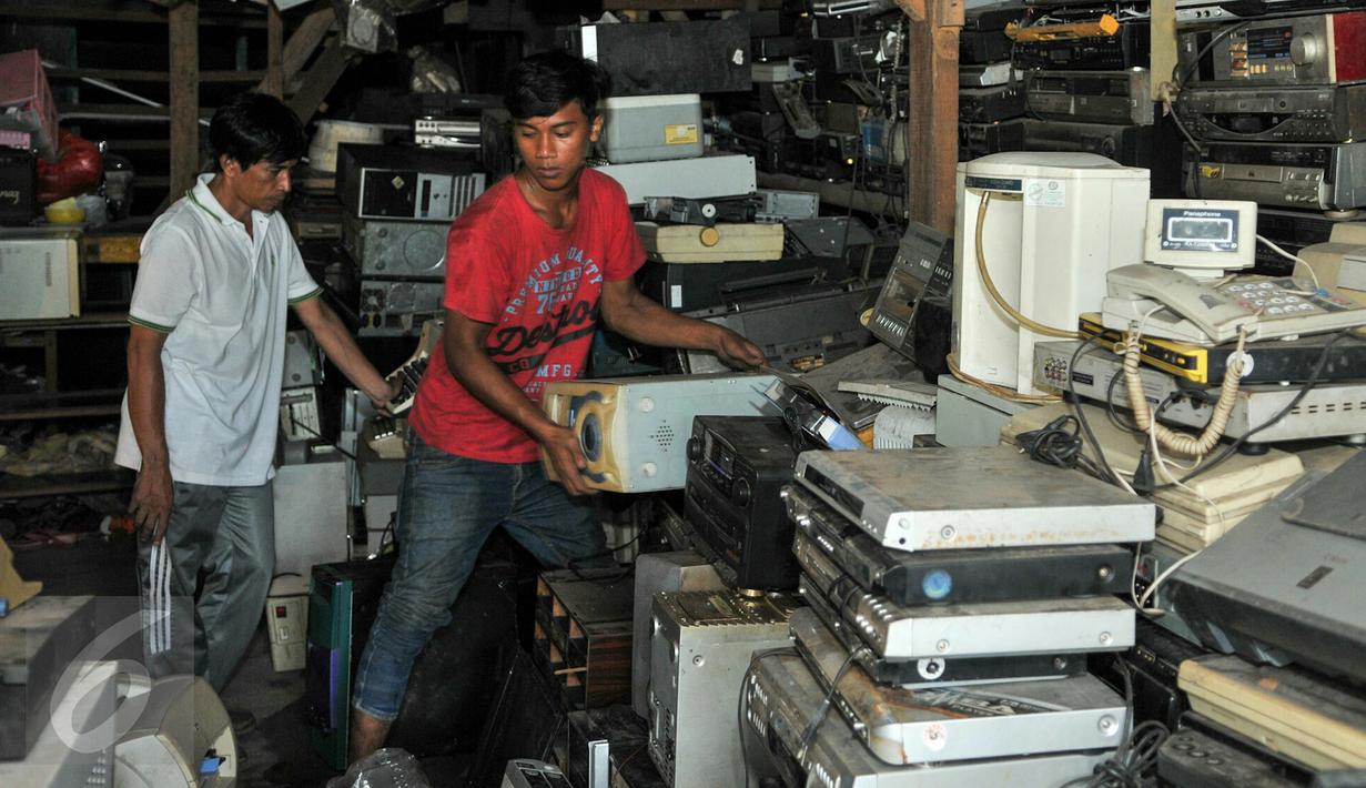 Nurcholis Agi (kiri) bersama pekerjanya saat merapihkan tumpukan barang-barang elektronik bekas disudut ruangan toko Mal Rongsok, Depok, Rabu (17/2). (Liputan6.com/Yoppy Renato)