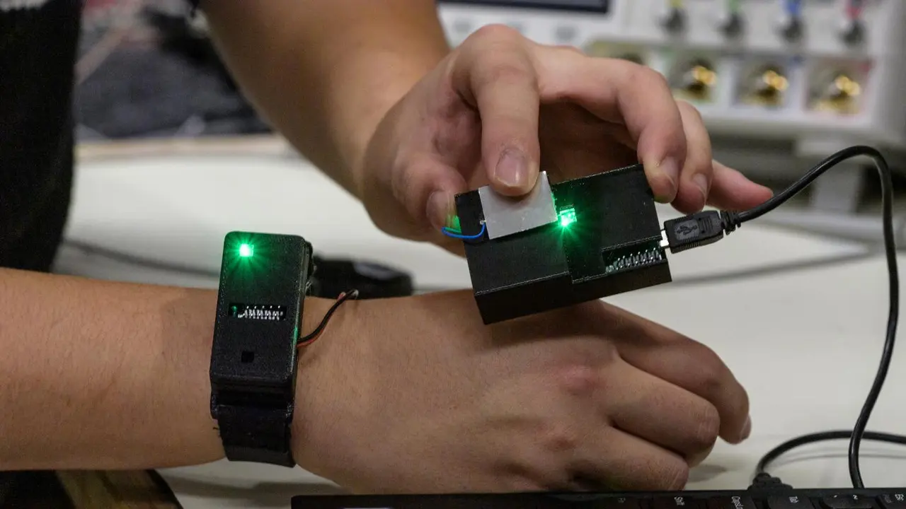 Seorang peneliti mentransfer informasi dari sebuah chip di jam tangan dengan menyentuh sensor yang terhubung ke laptop.