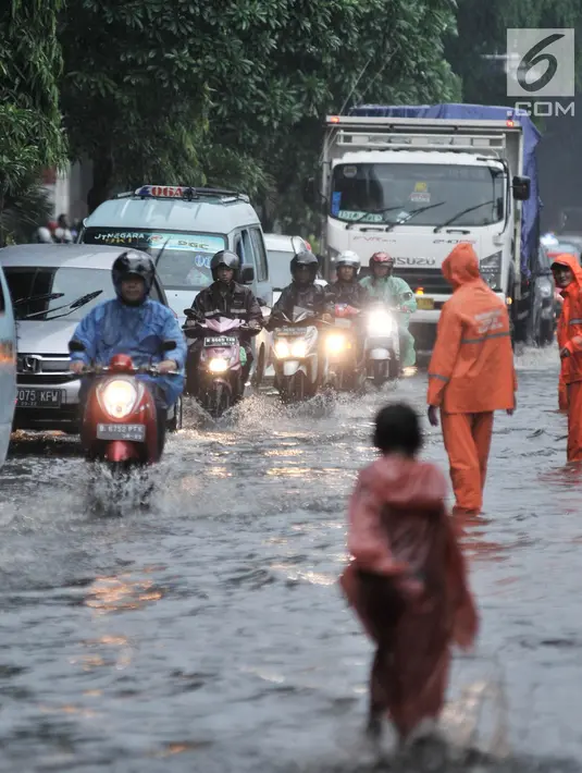 Petugas PPSU mengatur lajur kendaraan saat banjir menggenangi Jalan DI Panjaitan, Jakarta, Senin (3/12). Banjir juga disebabkan adanya pengerjaan proyek Tol Becakayu yang berada di jalan tersebut. (Merdeka.com/ Iqbal S. Nugroho)