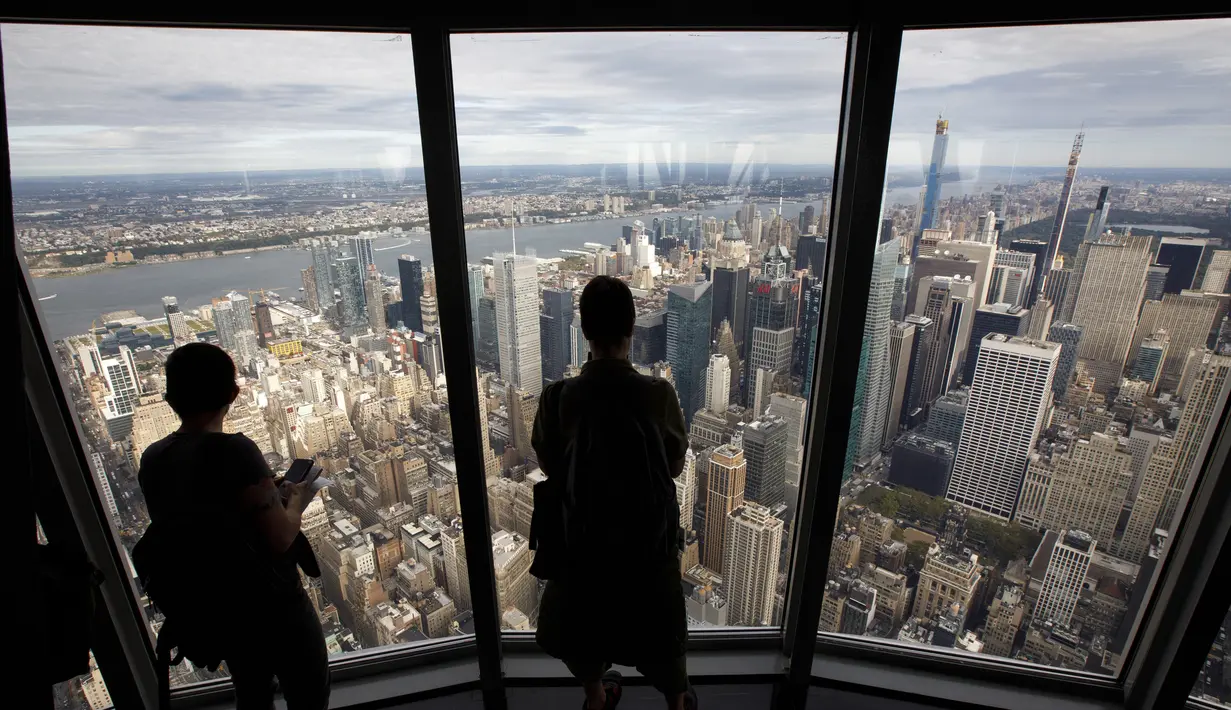 Pengunjung menikmati pemandangan Kota Manhattan dari ruangan observatorium di lantai 102 Gedung Empire State yang baru direnovasi di New York (10/10/2019). Dibuka untuk umum pada 12 Oktober, ruang observatorium ini berjarak 1.250 kaki di atas permukaan jalan. (AFP Photo/Drew Angerer)