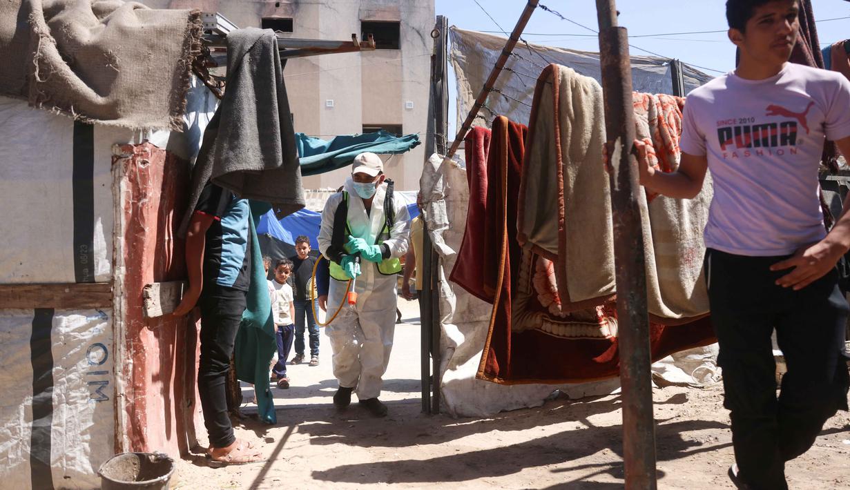 Kondisi tenda yang rapuh, banjir, serta cuaca dingin, yang membuat pengungsi kesulitan mendapatkan perlindungan yang layak. Tampak dalam foto, seorang pengungsi Palestina menyemprotkan cairan disinfektan pada jalan setapak dan tenda-tenda untuk membasmi serangga dan hewan pengerat di kamp pengungsian Khan Yunis, Jalur Gaza Selatan pada Rabu 22 April 2026. (Bashar Taleb/AFP)