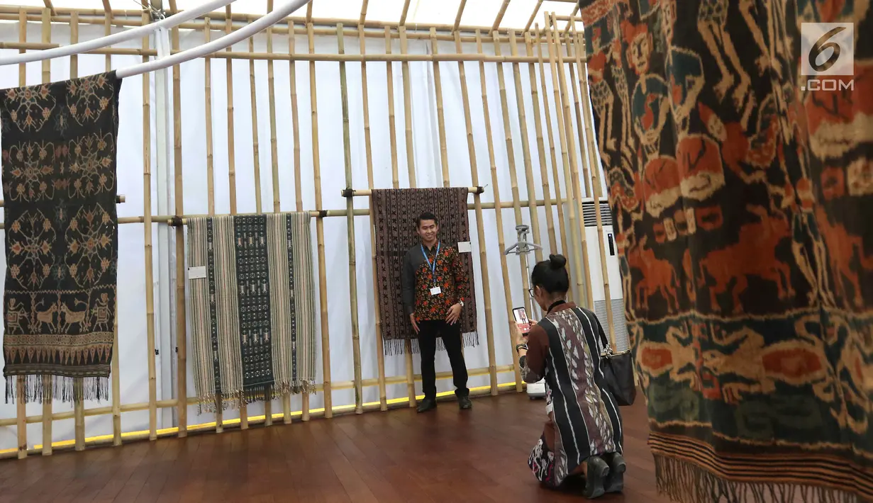 Peserta pertemuan tahunan IMF-Bank Dunia berfoto dengan kain tenun di Paviliun Indonesia, Bali, Senin (8/10). Pameran ini menampilkan pembangunan, bisnis, proyek strategis nasional, wisata hingga kekayaan seni budaya Tanah Air. (Liputan6.com/Angga Yuniar)