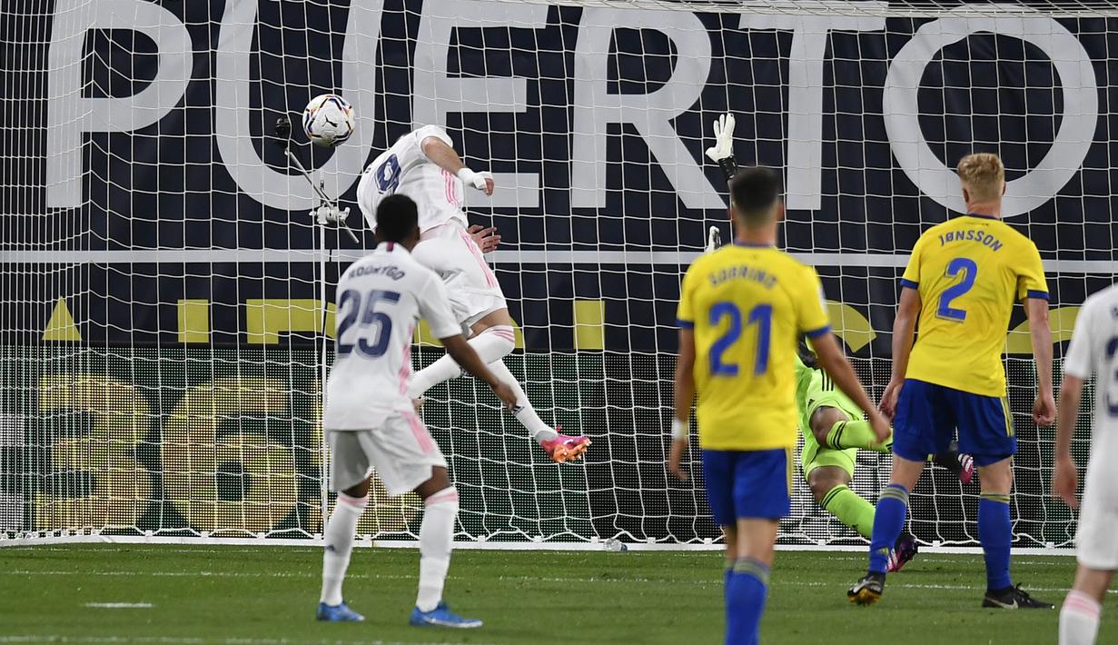 Pemain Real Madrid Karim Benzema (atas) mencetak gol ke gawang Cadiz melalui sundulan kepala pada pertandingan La Liga Spanyol di Stadion Ramon Carranza, Cadiz, Spanyol, Rabu (21/4/2021). Real Madrid menang 3-0. (AP Photo/Jose Breton)