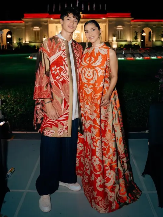 Maudy Koesnaedi tampil mewah dengan dress tanpa lengan waena merah dengan motif batik warna keemasan. [@maudykoesnaedi]