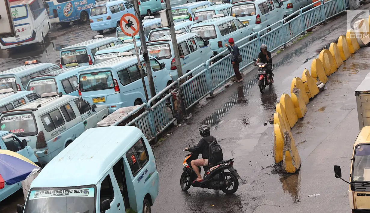 Pengendara sepeda motor melintasi jalur angkutan umum di Terminal Kampung Melayu, Jakarta, Rabu (6/2). Sejumlah pengendara nekat menerobos masuk terminal untuk memotong jalur guna memersingkat waktu tempuh. (Liputan6.com/Immanuel Antonius)