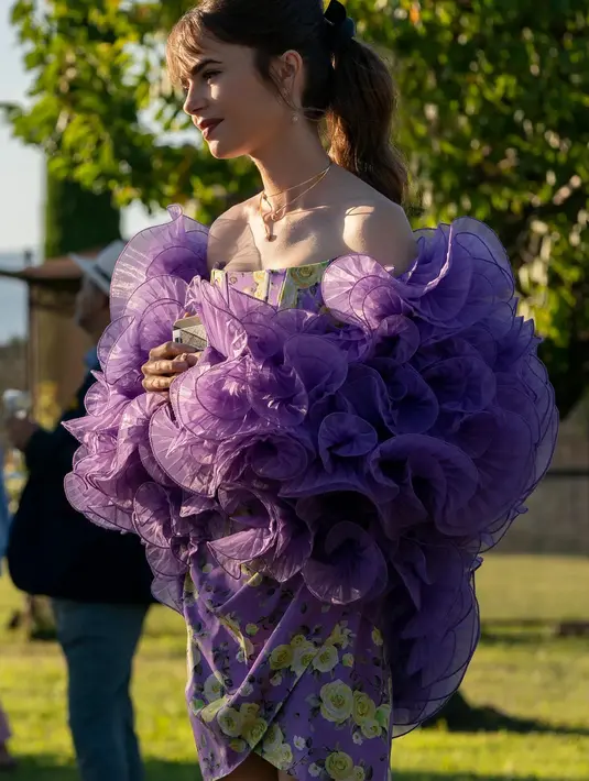 Ini adalah penampilan Lily Collins di Emily in Paris season 3. Ia mengenakan Guiseppedi Morabito mini dengan THAT H&M X Iris Apfel flounced jacket. Foto: Netflix.