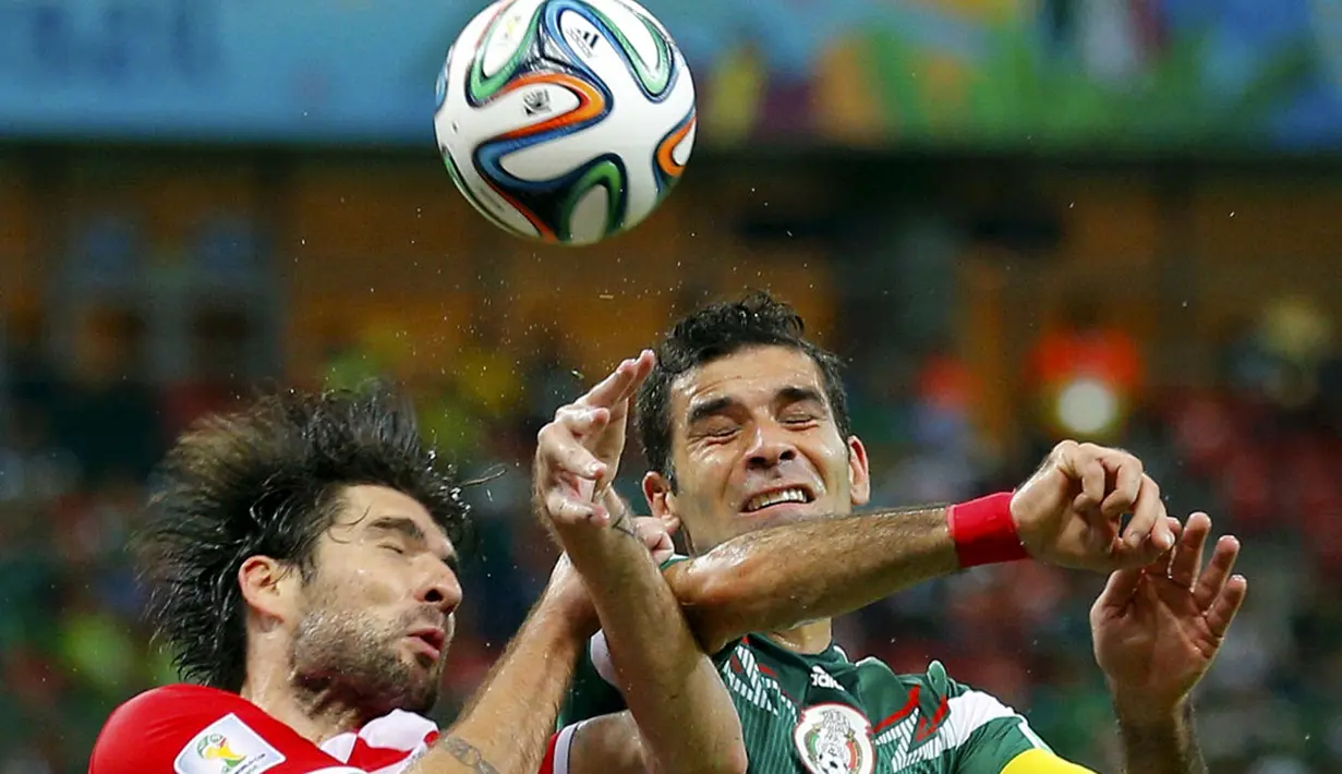Pemain belakang Kroasia, Vedran Corluka (kiri) berebut bola dengan gelandang Meksiko, Rafael Marquez, di laga penutup penyisihan Piala Dunia Grup A di Stadion Pernambuco, Recife, Brasil, (24/6/2014). (REUTERS/Brian Snyder)