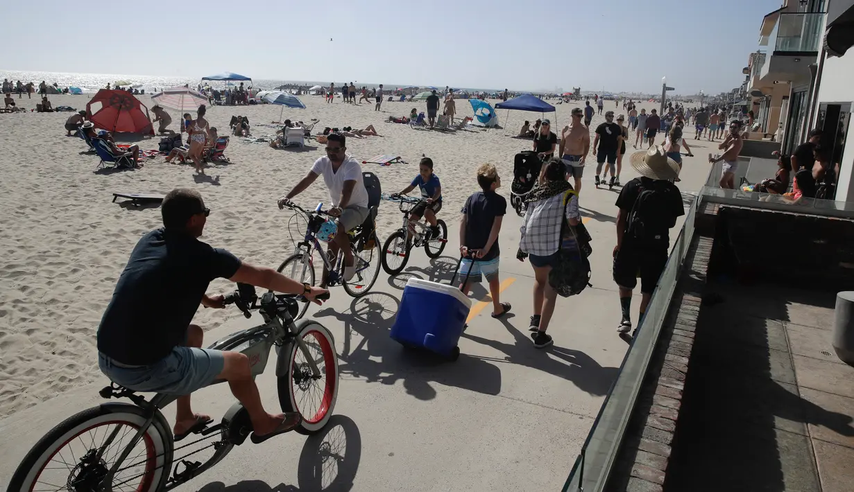 Pengunjung menggunakan jalur sepeda dan berjalan di Pantai Newport selama masa pandemi covid-19 di California pada Minggu (24/5/2020). Warga Amerika Serikat memilih berjemur di pantai ketika angka kematian akibat virus corona di negara itu mendekati 100.000 orang. (AP/Marcio Jose Sanchez)