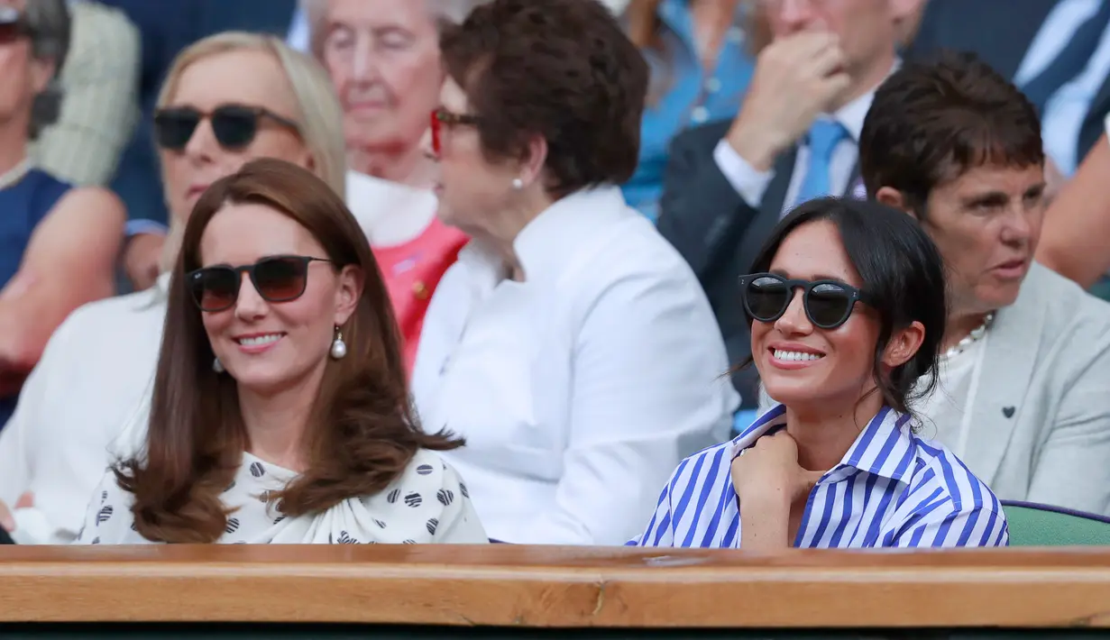 Duchess of Cambridge Kate Middleton dan Duchess of Sussex Meghan Markle tersenyum saat menyaksikan pertandingan Serena Williams dan Angelique Kerber di kejuaraan  tenis Wimbledon di London, Inggris, (14/7). (AP Photo/Andrew Couldridge)