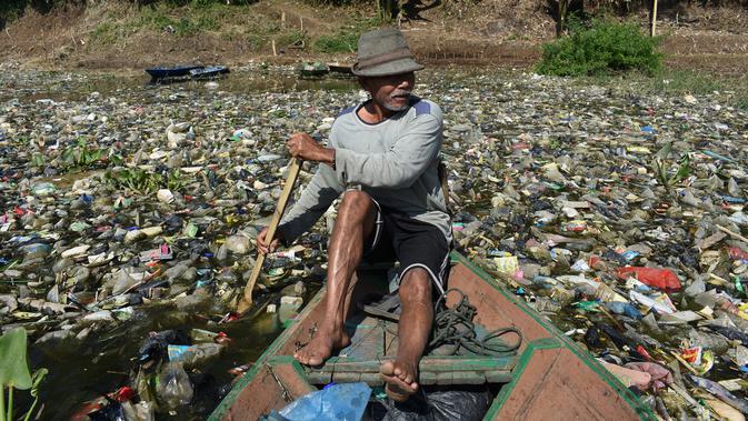 Warga menggunakan perahu untuk memilah sampah plastik di aliran Sungai Citarum, Bandung, Rabu (26/6/2019). Menurut warga di kawasan itu volume sampah kiriman yang kerap menumpuk mulai mengalami penurunan setelah beberapa waktu lalu sempat menutupi permukaan aliran Sungai Citarum (Timur Matahari/AFP)