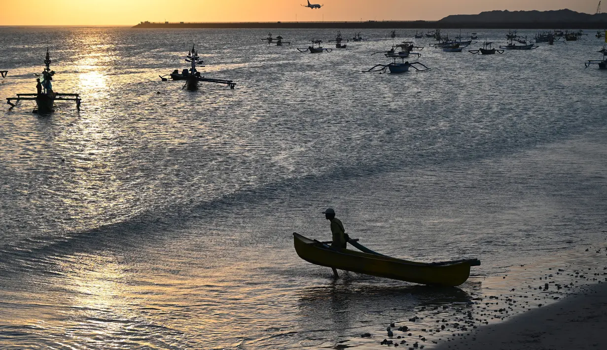 Seorang nelayan membawa perahunya untuk pergi memancing ikan di Kedonganan, Denpasar, Bali (15/7/2019). Batas wilayah Kelurahan Kedonganan terletak di ujung utara Kecamatan Kuta. (AFP Photo/Sonny Tumbelaka)