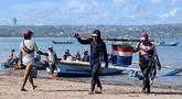 Para pekerja membawa ikan setelah para nelayan menurunkan hasil tangkapan mereka dari perahu di pantai Kedonganan dekat Denpasar, Bali, pada Jumat 10 April 2026. Provinsi Bali memiliki sejumlah pelabuhan yang berperan penting dalam mendukung kegiatan perikanan dan kelautan. (SONNY TUMBELAKA/AFP)