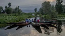 Laki-laki Kashmir mengobrol saat beristirahat sambil menjual produk mereka di pasar sayur terapung di Danau Dal, Srinagar, Kashmir, India, Sabtu (7/8/2021). Pedagang menghabiskan waktu bertahun-tahun untuk memelihara Danau Dal dari rumput liar. (AP Photo/Dar Yasin)