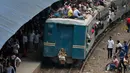 Penumpang berada di atap kereta api saat akan pulang kampung di stasiun kereta api di Dhaka, Bangladesh, (22/6). Ribuan yang bekerja di Dhaka pulang ke kampung halamannya untuk merayakan lebaran bersama keluarganya. (AP Photo/A.M.Ahad)