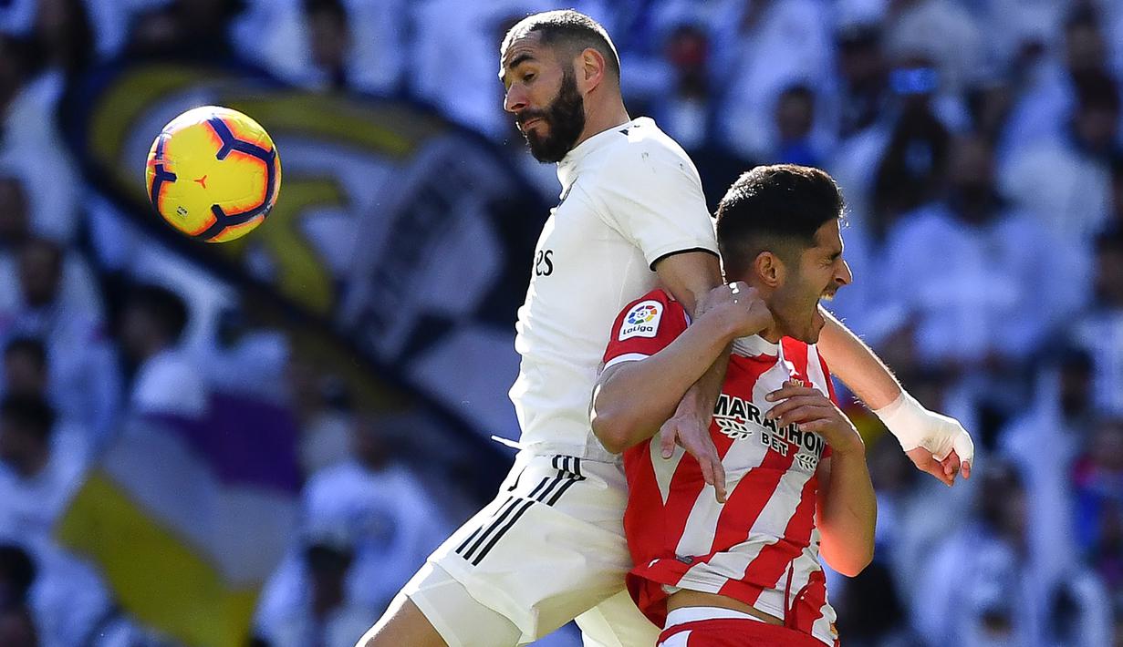 Striker Real Madrid, Karim Benzema, berebut bola dengan bek Girona, Juanpe Ramirez, pada laga La Liga di Stadion Santiago Bernabeu, Madrid, Minggu (17/2). Madrid kalah 1-2 dari Girona. (AFP/Gabriel Bouys)