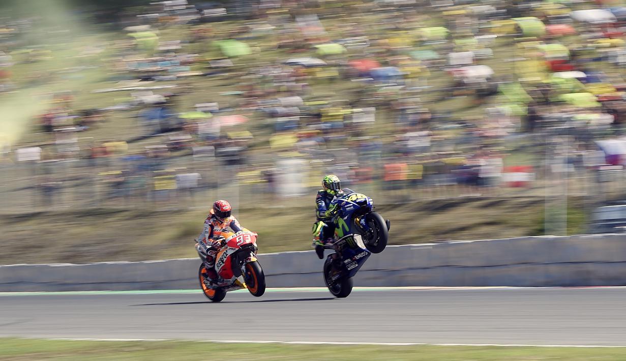 Pebalap Repsol Honda Team, Marc Marquez (kiri) dan Movistar Yamaha MotoGP, Valentino Rossi mengangkat roda saat kualifikasi MotoGp di Sirkuit Brno, (5/8/2017). Marc Marquez menjadi juara pada balapan tersebut. (AFP/Michal Cizek)