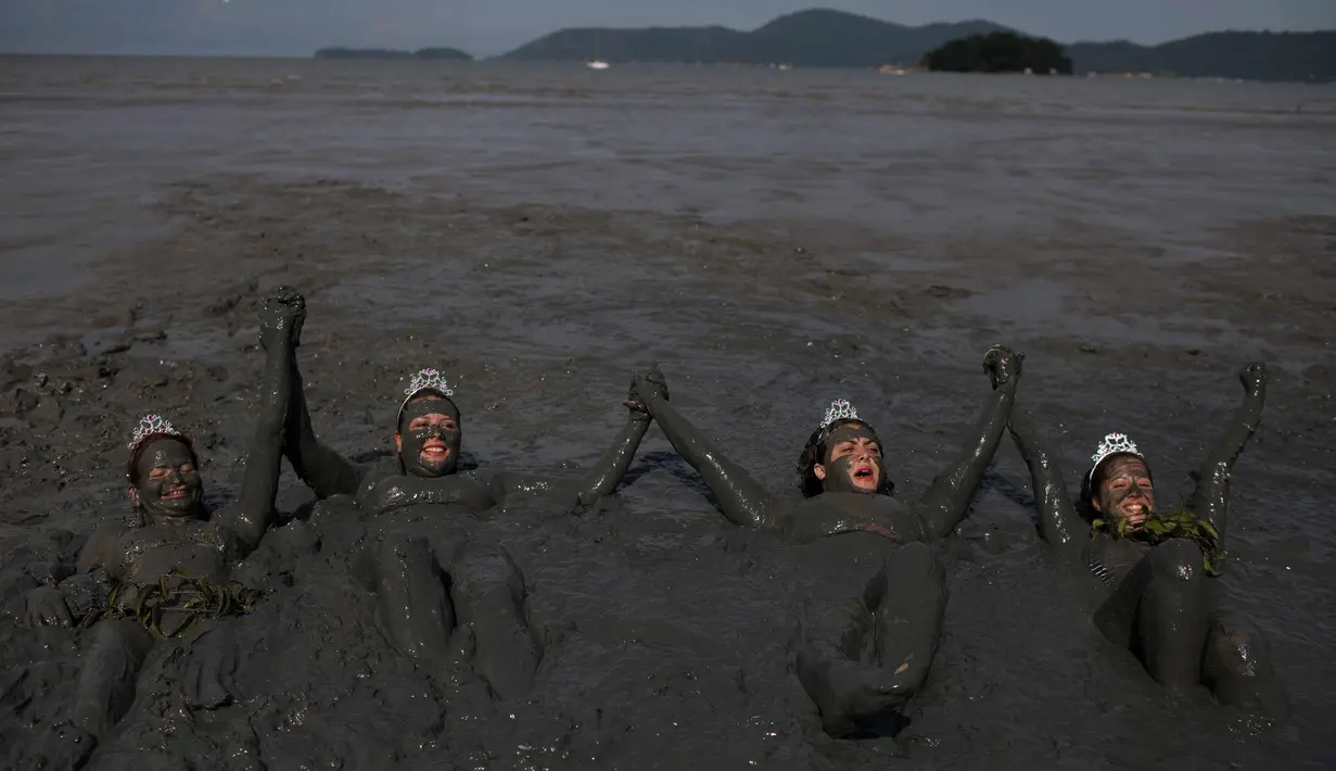 Peserta berendam di lumpur selama pesta karnaval "Bloco da Lama" atau "Lumpur Lumpur" di Paraty, Brasil, (10/2). Ratusan orang berendam dan saling menyerang menggunakan lumpur di pesta pantai Karnaval tersebut. (AP Photo / Leo Correa)