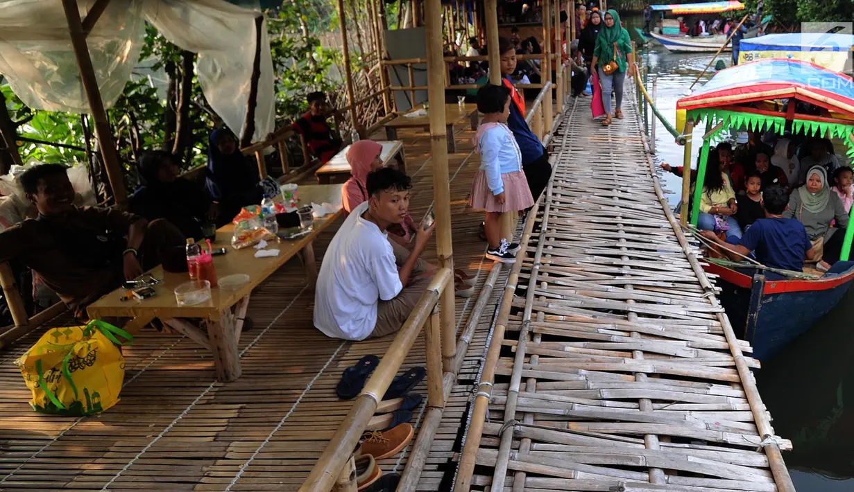 Wisatawan saat mengunjungi hutan mangrove di Sungai Rindu, Desa Hurip Jaya, Babelan, Bekasi, Jumat (7/6/2019).Dengan membayar perahu Rp 10 ribu per orang, wisatawan sudah bisa berkeliling sambil menikmati kopi dalam hutan mangrove. (merdeka.com/Arie Basuki)