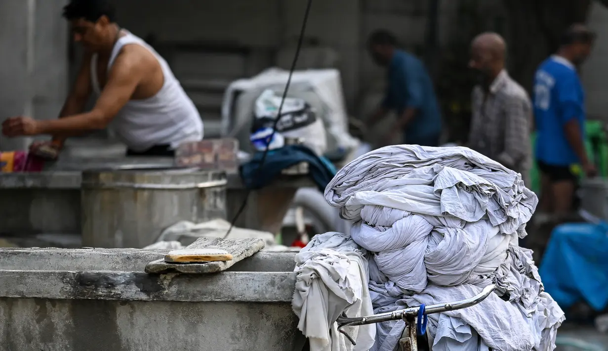 Pakaian yang sudah dicuci disimpan di atas sepeda di binatu terbuka, yang secara lokal disebut 'Dhobi Ghat' di New Delhi, India pada 14 Maret 2022. Dhobi Ghat adalah tempat yang menyediakan layanan cuci dengan cara tradisional. (Money SHARMA / AFP)