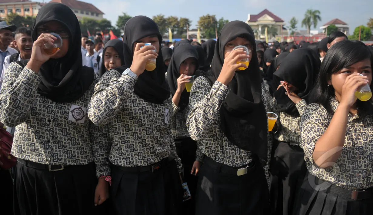 Sejumlah pelajar saat minum jamu bersama di Alun-Alun Satya Negara Sukoharjo, Jawa Tengah, Rabu (1/4/2015). Kegiatan tersebut dalam rangka pelestarian jamu ke masyarakat nasional maupun internasional. (Liputan6.com/Johan Tallo)