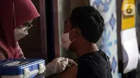 Petugas kesehatan menyuntikkan vaksin booster COVID-19 kepada seorang pria di Pasar Tanah Abang Blok A, Jakarta, Senin (4/4/2022). Vaksinasi yang diselenggarakan Polri ini diikuti warga sekitar dan pedagang Pasar Tanah Abang yang berencana mudik Lebaran. (Liputan6.com/Faizal Fanani)