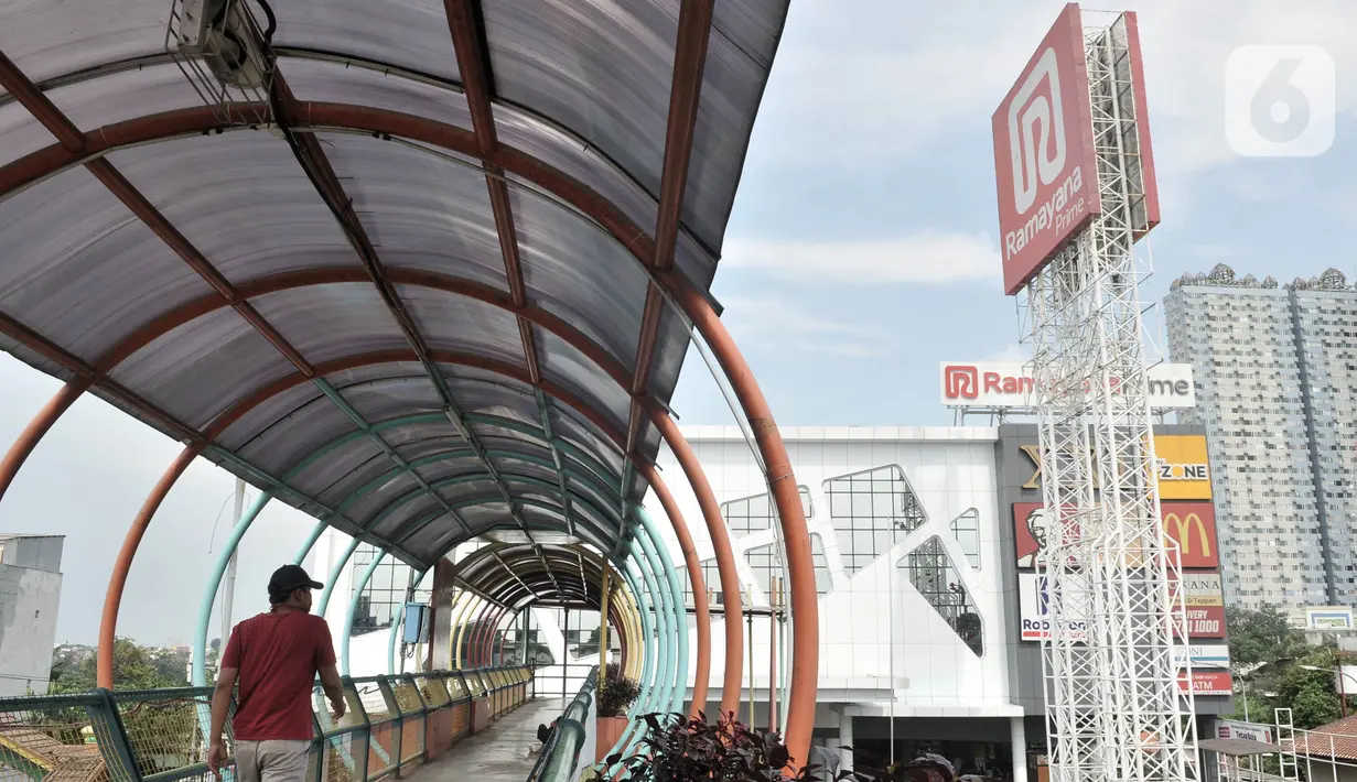Warga melintasi jembatan penyeberangan dekat gerai Ramayana yang tutup di City Plaza Depok, Rabu (8/4/2020). Ramayana Departement Store menutup operasionalnya di City Plaza Depok, dimana 87 karyawan terkena PHK lantaran pandemi Covid-19 menyebabkan omzet penjualan menurun (merdeka.com/Iqbal Nugroho)