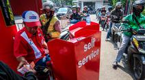 Seorang pekerja SPBU (kiri) menerima pembayaran dari pengendara yang mengantre untuk mengisi bahan bakar sepeda motor mereka di sebuah Stasiun Pengisian Bahan Bakar Umum (SPBU), Jakarta pada Rabu 1 April 2026. Pemerintah resmi tidak mengubah harga Bahan Bakar Minyak (BBM) di dalam negeri, baik harga BBM subsidi maupun non subsidi. (BAY ISMOYO/AFP)