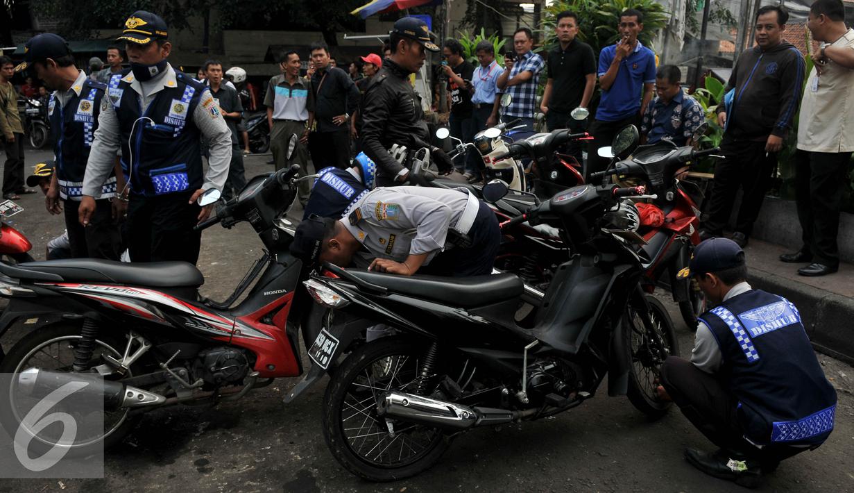 Petugas Dishub, mencabut pentil sebuah sepeda motor yang nekat parkir liar di Jakarta, Jumat (12/6/2015). Razia gabungan Dishub, Garnisun dan Satlantas bertujuan untuk mengantisipasi arus lalu lintas yang kerap macet. (Liputan6.com/Johan Tallo)