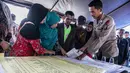 Anggota keluarga melihat daftar nama korban tenggelamnya KM Sinar Bangun di pelabuhan feri Danau Toba, Sumatera Utara, Rabu (20/6). Basarnas menerjunkan 70 personel untuk melakukan pencariankorban tenggelamnya KM Sinar Bangun. (AFP PHOTO/IVAN DAMANIK)