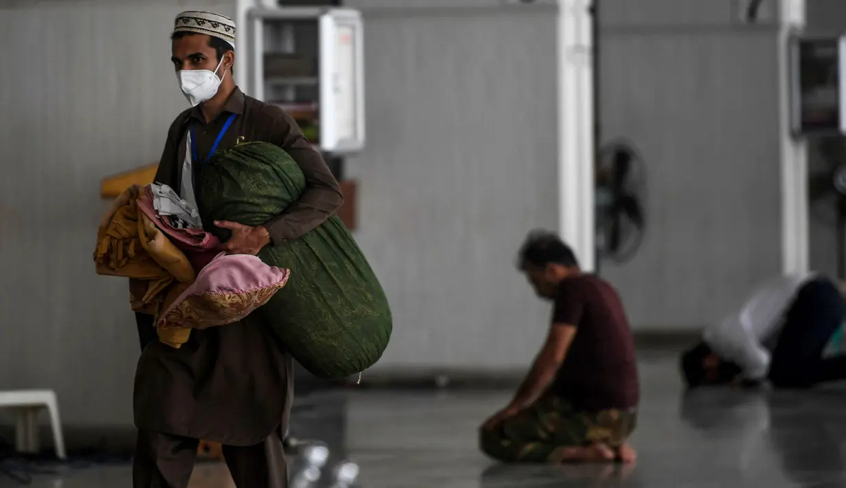 Seorang umat muslim dengan mengenakan masker membawa barang-barangnya saat tiba untuk beritikaf di Masjid Agung Faisal di Islamabad, Pakistan, Kamis (14/5/2020). Itikaf adalah berdiam diri di masjid untuk mendekatkan diri kepada Allah swt pada sepuluh hari terakhir bulan Ramadan (Aamir QURESHI /AFP)