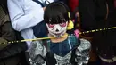 Seorang anak kecil berpakaian seperti "Catrina" ambil bagian dalam parade Hari Orang Mati di Reforma Avenue, Mexico City, 21 Oktober 2018. Banyak orang yang menggenakan kostum dan hiasan serba tongkorak yang memenuhi jalanan. (RODRIGO ARANGUA/AFP)