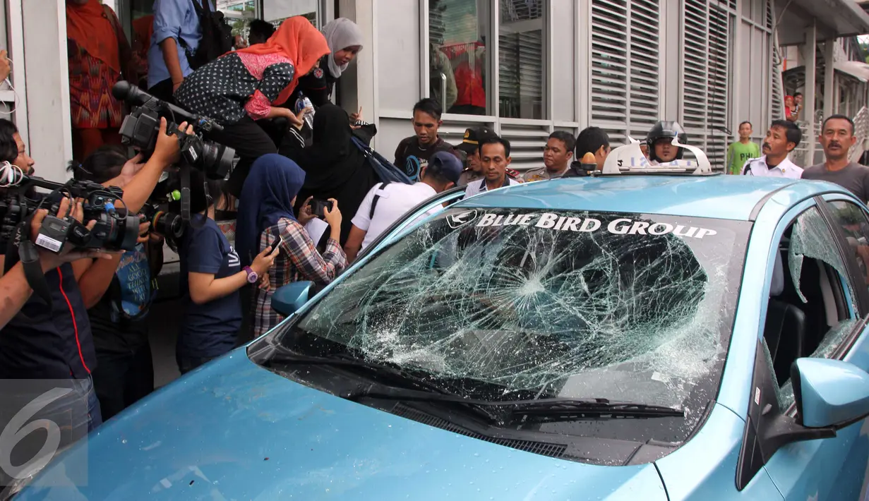 Sebuah taksi mengalami kerusakan usai diamuk massa di kawasan Kuningan, Jakarta, Selasa (22/3). Aksi anarkis ini adalah buntut dari demo yang dilakukan sejumlah sopir taksi. (Liputan6.com/Helmi Afandi)