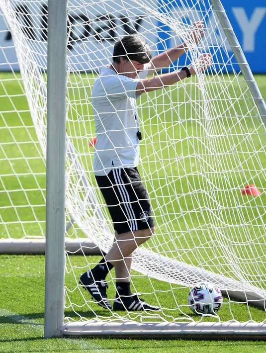 Pelatih Jerman Joachim Loew mengambil bola dari gawang saat sesi latihan MD-1 di Herzogenaurach, Jerman, Senin (28/6/2021). Jerman akan melawan Inggris pada babak 16 besar Euro 2020. (Christof STACHE/AFP)