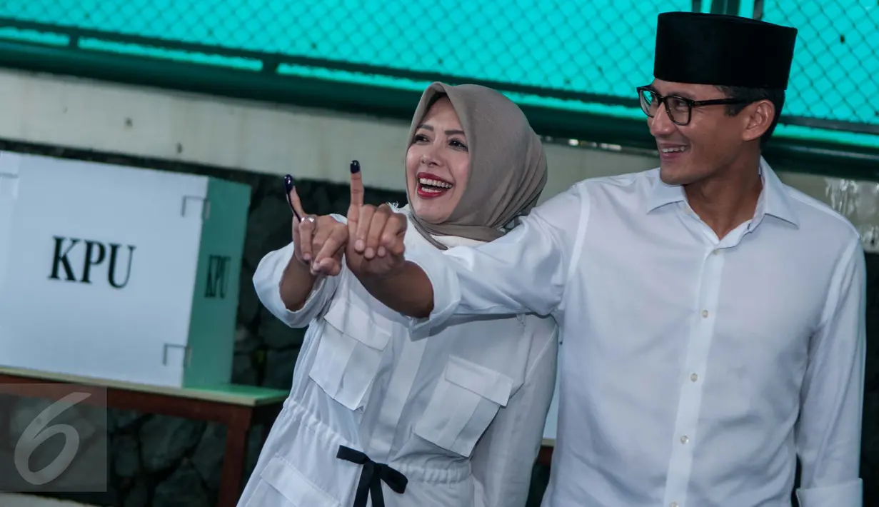 Calon Wakil Gubernur DKI Sandiaga Uno bersama istrinya menunjukkan jari mereka yang telah dicelup tinta usai memberikan suara pada Pilkada DKI 2017 di TPS 01 Kelurahan Selong, Kebayoran Baru, Jakarta Selatan, Rabu (15/2). (Liputan6.com/Gempur M Surya)