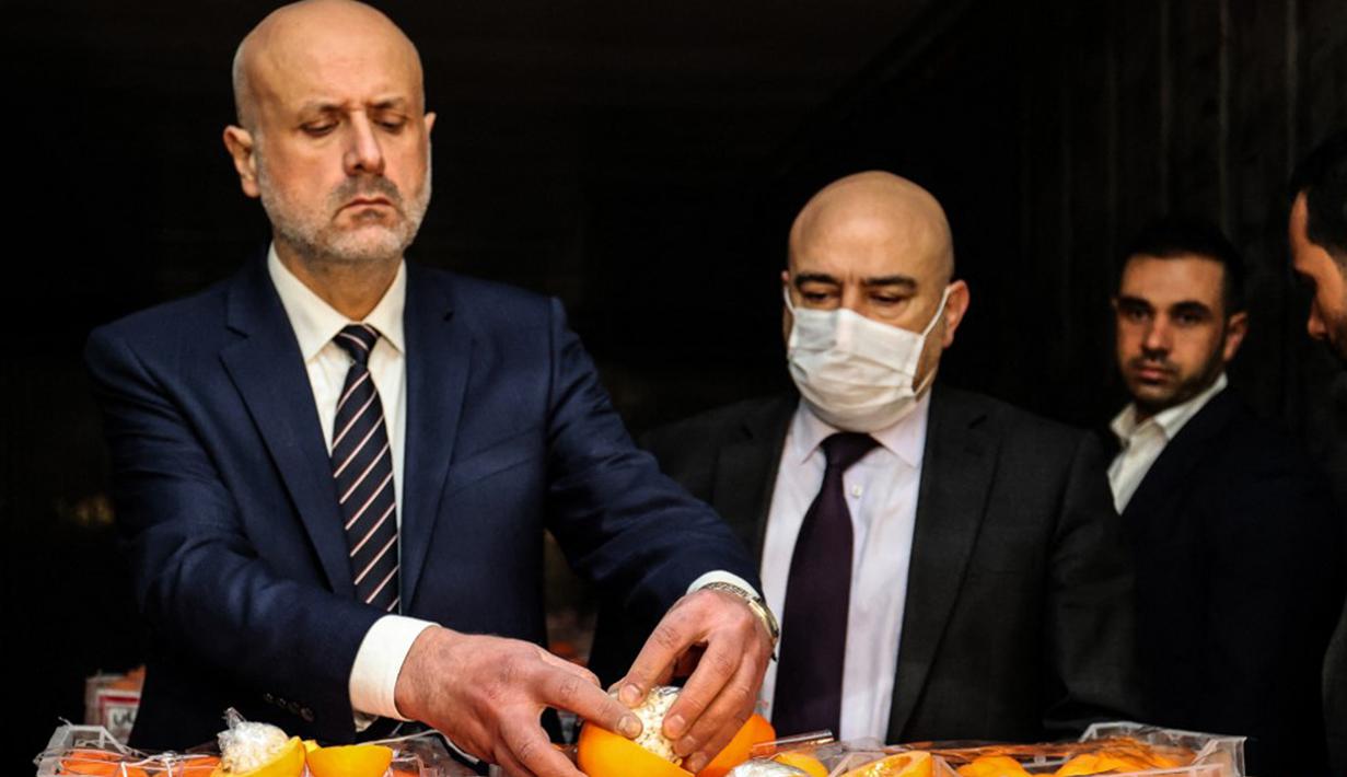 Menteri Dalam Negeri Lebanon Bassan al-Mawlawi (kiri) memeriksa salah satu jeruk palsu berisi pil Captagon di Pelabuhan Beirut, Lebanon, 29 Desember 2021. Bea Cukai Lebanon menyita sembilan juta pil Captagon dalam jeruk palsu yang ditujukan ke salah satu negara Teluk. (ANWAR AMRO/AFP)