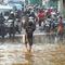 Anak-anak bermain air saat banjir meggenangi Jalan Raya Bogor di depan Pasar Induk Kramat Jati, Jakarta, Kamis (30/11/2023). (merdeka.com/Arie Basuki)