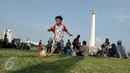 Seorang anak bermain bola di halaman Munomen Nasional (Monas), Jakarta, Kamis (7/7). Libur kedua Lebaran dimanfaatkan warga untuk bekunjung ke lokasi wisata bersama keluarga. (Liputan6.com/Yoppy Renato)