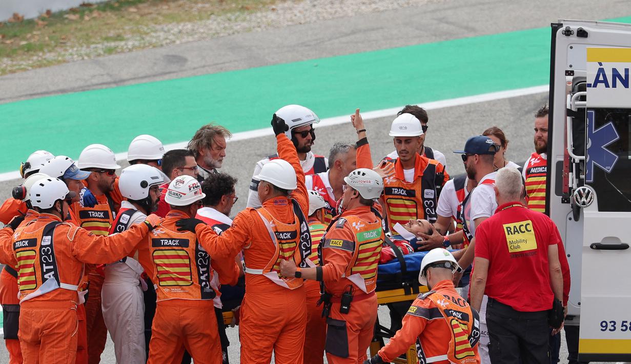 Pecco tampak diangkut ambulans. Informasi dari tayangan langsung MotoGP, Pecco dilarikan ke pusat medis. Namun, kabarnya Pecco masih sadarkan diri. Marshal juga memberikan acungan jempol ke kamera saat membawa Pecco ke ambulans. (AFP/Lluis Gene)