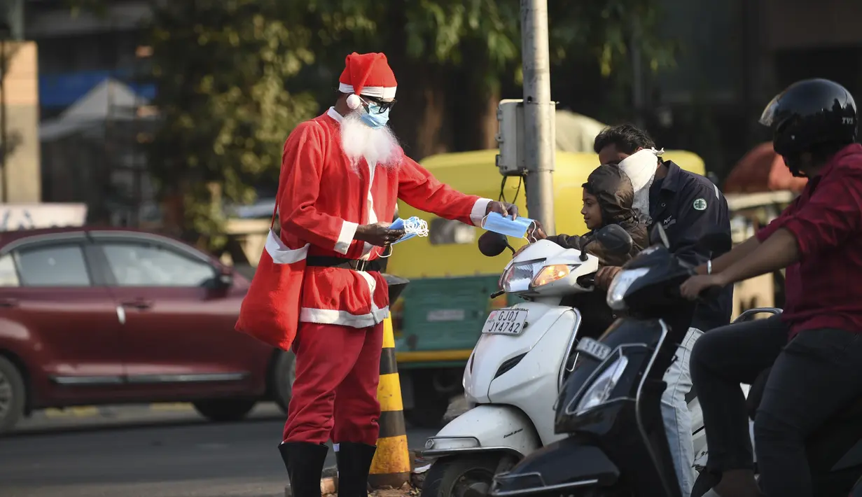 Aksi presiden Angel Foundation dan pekerja sosial, Rufas Christian, yang berpakaian Sinterklas memberikan masker kepada pengendara di persimpangan lalu lintas di Ahmedabad, India, Kamis (17/12/2020). India sejauh ini telah mencatat hampir 10 juta kasus Covid-19. (SAM PANTHAKY/AFP)