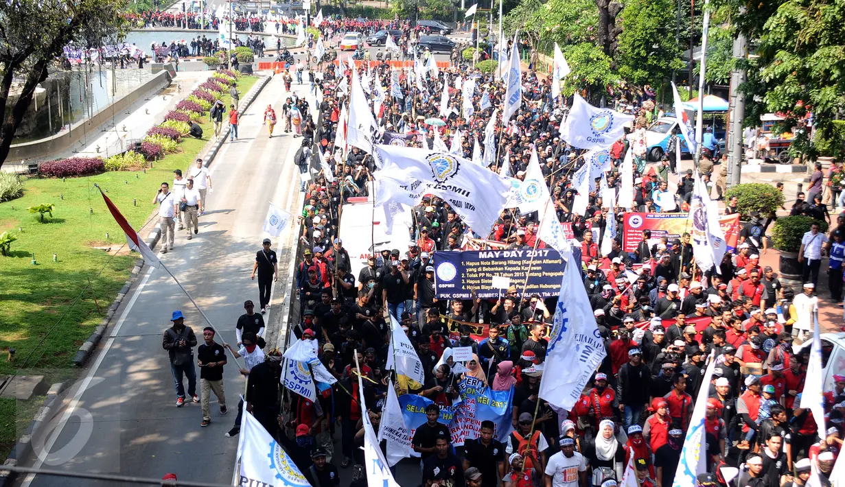 Massa buruh berjalan memasuki kawasan Jalan Medan Merdeka Barat, Senin (1/5). Aksi perayaan Hari Buruh Internasional oleh ribuan buruh tertahan di depan Kementerian Pariwisata akibat penutupan Jalan medan Merdeka Barat. (Liputan6.com/Helmi Fithriansyah)