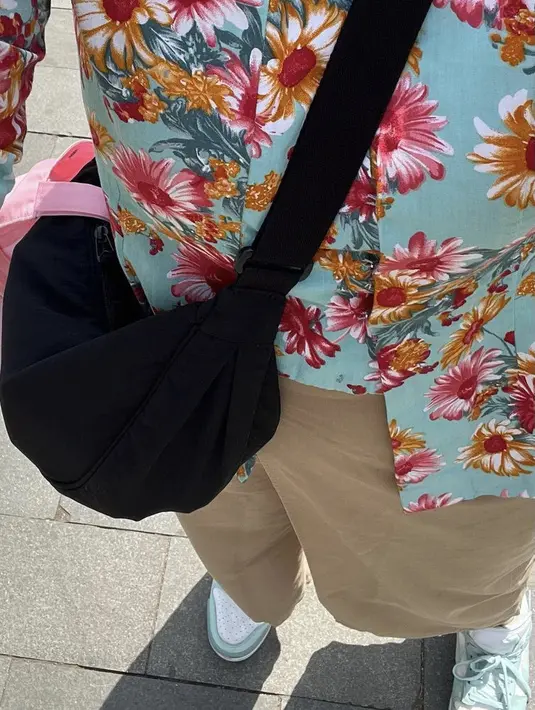 Ia juga mengenakan tas hitam sling bag, sambil membawa topi cap warna pink. [@camilliazr]