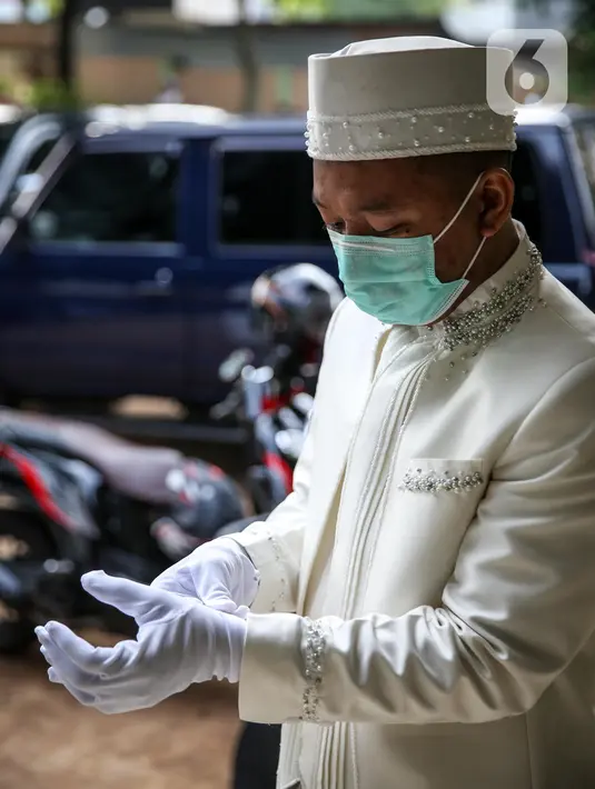 Pengantin pria memakai sarung tangan sebelum melaksanakan prosesi akad nikah di KUA Jagakarsa, Jakarta, Sabtu (6/6/2020). Pada masa penerapan PSBB transisi, pihak KUA tersebut menikahkan sebanyak delapan hingga 10 pasangan pengantin per hari. (Liputan6.com/Faizal Fanani)