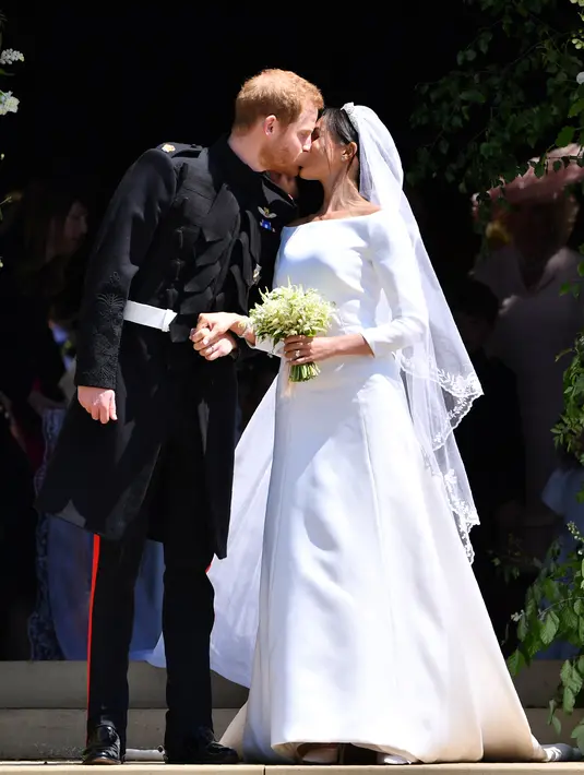 Pangeran Harry mencium istrinya, Meghan Markle saat mereka berangkat dari Pintu Barat St George's Chapel, Kastil Windsor, Inggris, Sabtu (19/5). Pangeran Harry dan Meghan Markle telah resmi menikah. (Ben STANSALL/POOL/AFP)