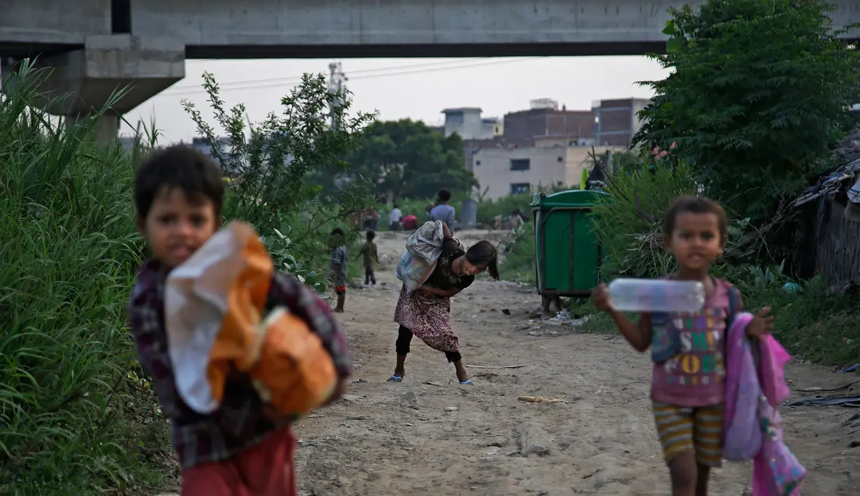 Sejumlah anak pengungsi Rohingya membawa karung saat kembali ke gubuknya di kamp pengungsi, New Delhi, India (12/9). Sekitar 40.000 warga Rohingya yang pergi dari Myanmar. Tapi hanya 16.500 yang terdaftar di agen pengungsi U.N. (AP Photo/Altaf Qadri)
