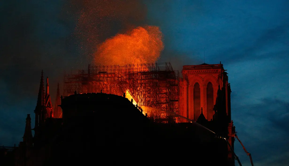 Petugas pemadam kebakaran berusaha memadamkan api dari Gereja Katedral Notre-Dame di kota Paris, Prancis, pada Senin (15/4). Katedral ini termasuk salah satu gereja roman katolik yang terkenal di seluruh dunia dengan luas total bangunanya mencapai 6.144 meter persegi. (AP Photo/Francois Mori)