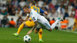 Gelandang Real Madrid, Toni Kroos saat dilanggar pemain APOEL Nicosia, Roland Sallai saat bertanding pada penyisihan Grup H Liga Champions di stadion Santiago Bernabeu, Spanyol, (13/9). Madrid menang telak 3-0 atas APOEL. (AP Photo/Francisco Seco)