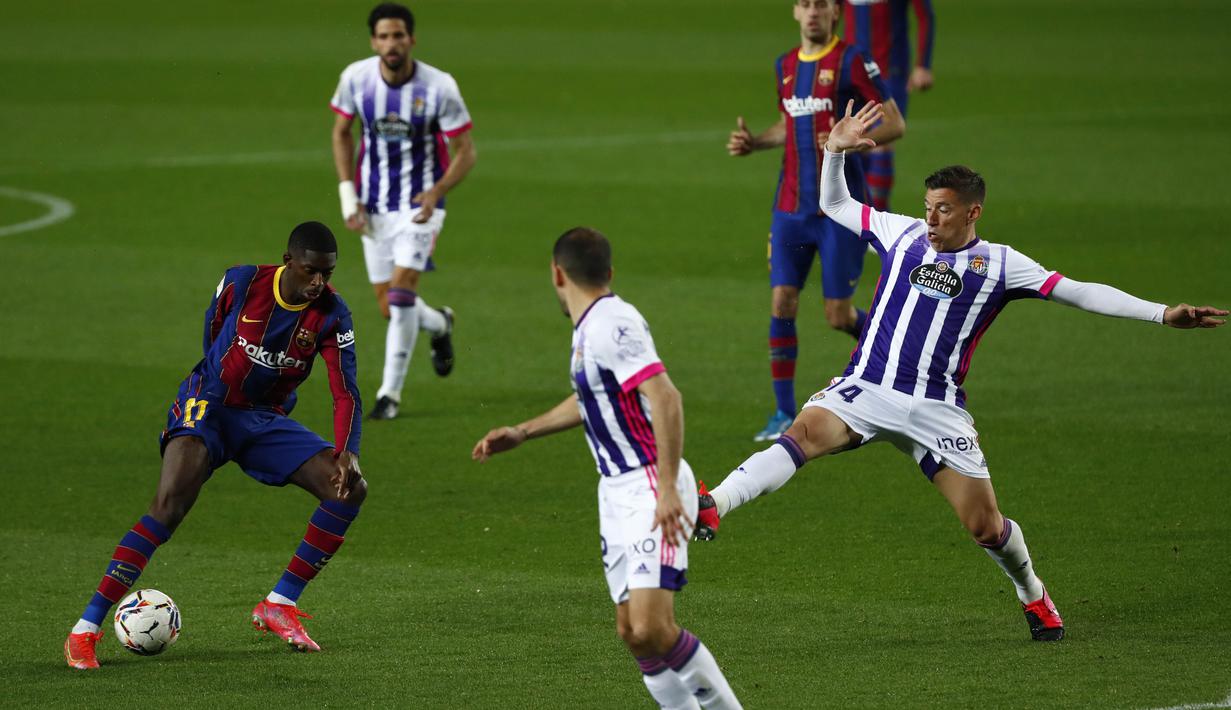 Penyerang Barcelona, Ousmane Dembele, berusaha melewati pemain Real Valladolid pada laga Liga Spanyol di Stadion Camp Nou, Selasa (6/4/2021). Barcelona menang dengan skor 1-0. (AP Photo/Joan Monfort)